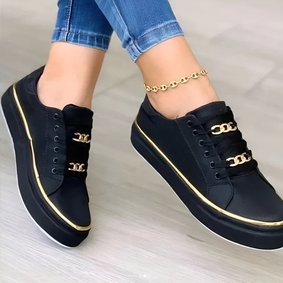 Detalle cercano de las zapatillas negras de plataforma, con adornos metálicos en los cordones y una línea dorada alrededor de la suela.