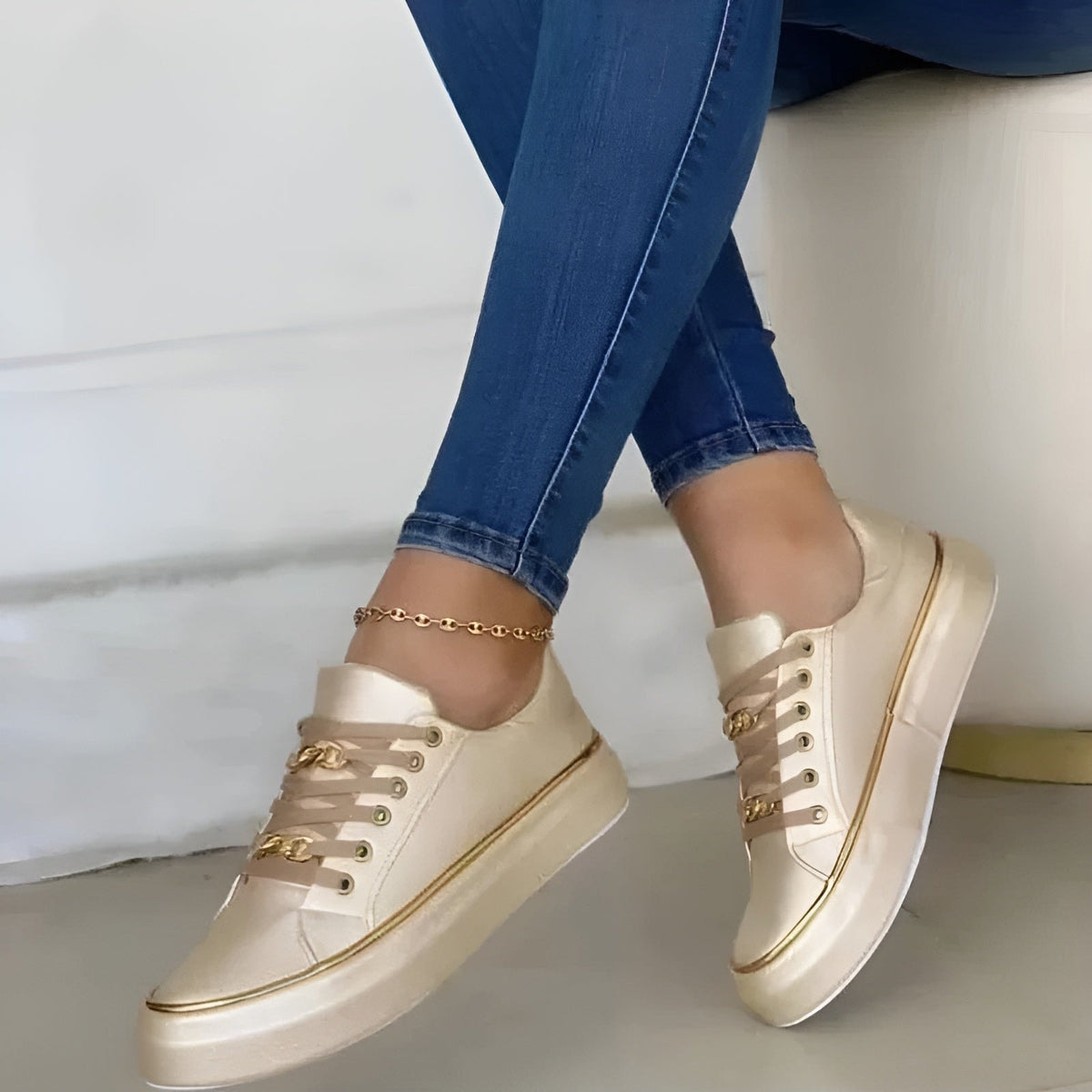 Zapatillas en tono crema de plataforma con cordones, ojales y ribete dorados, mostradas en movimiento.