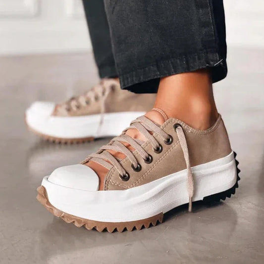 Zapatilla de plataforma color beige con puntera reforzada blanca, cordones y suela dentada en primer plano.