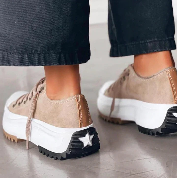 Vista trasera de las zapatillas beige con plataformas blancas, talones reforzados y suelas dentadas negras con detalle de estrella.