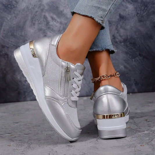 Zapatillas de plataforma metalizadas en tono plateado, mostradas en vista lateral y posterior con cordones blancos, cremalleras laterales y detalles dorados.
