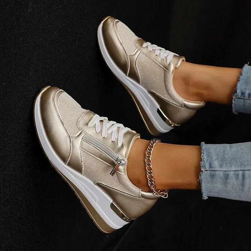 Vista superior de las zapatillas metalizadas color champán, donde se aprecian los cordones blancos, las cremalleras laterales y la plataforma.