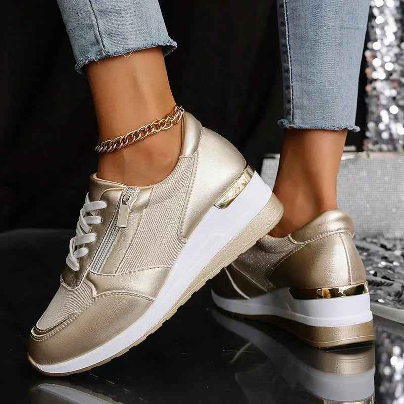 Zapatillas metalizadas color champán mostradas desde el lateral y la parte posterior, con plataformas blancas y detalles dorados en el talón.