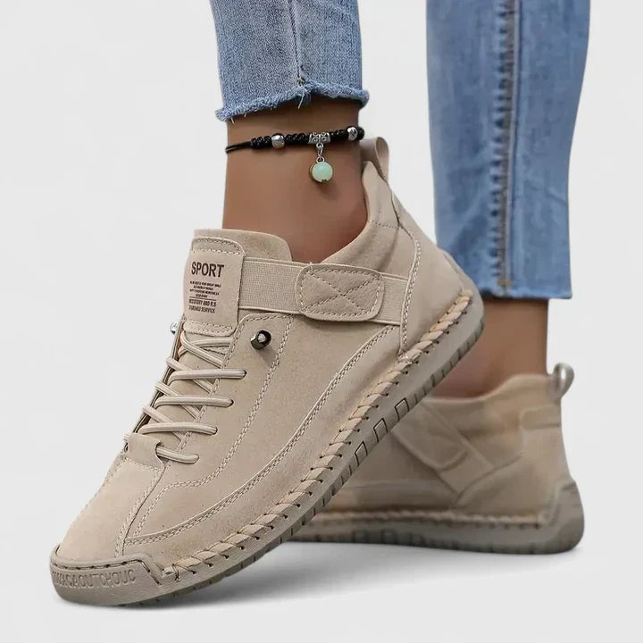 Zapatillas planas beige con cordones y cierre ajustable, vistas desde un ángulo lateral mientras se llevan puestas.