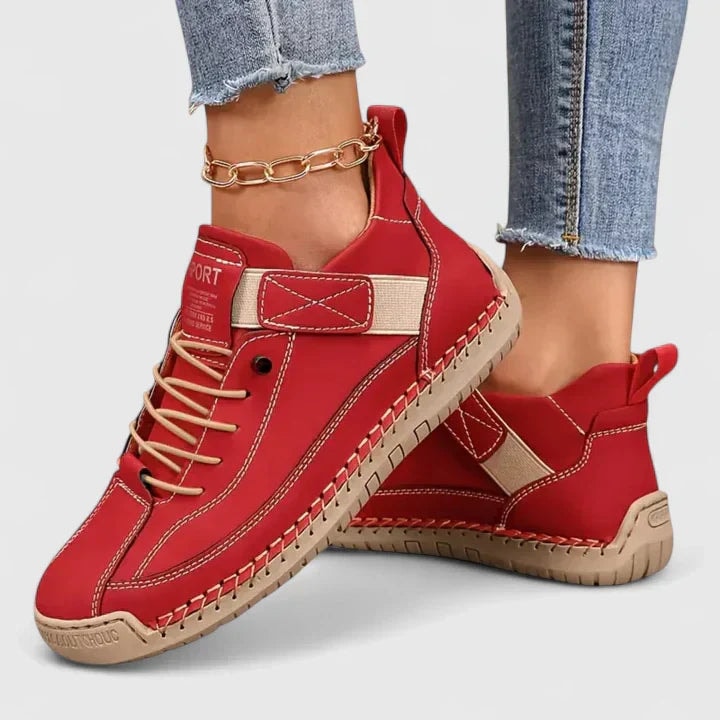 Zapatillas planas rojas con detalles en contraste, cordones y cierre ajustable, mostradas en los pies.