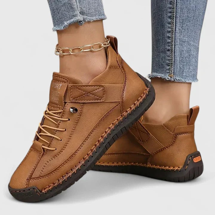 Zapatillas planas marrones con cordones, cierre ajustable y suela oscura, mostradas desde una vista lateral.