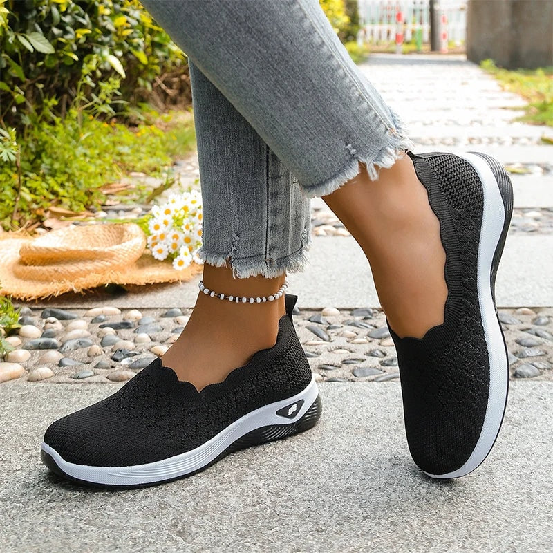 Vista lateral de las zapatillas negras, con una apoyada y la otra elevada para mostrar la suela.