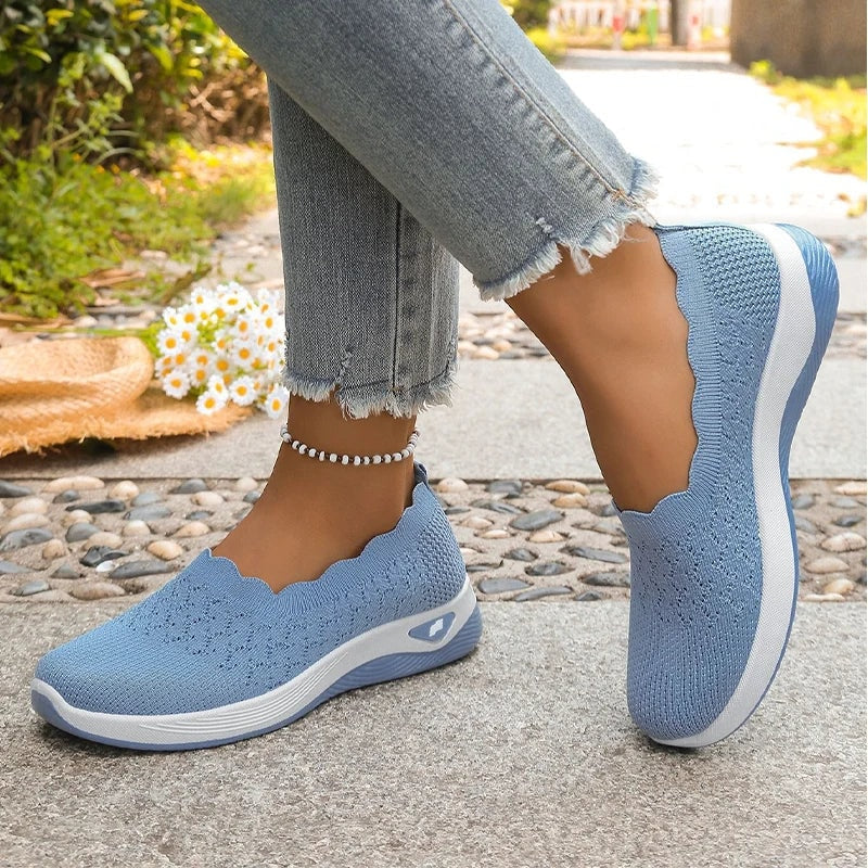 Zapatillas slip-on azules en vista lateral, con un pie apoyado y el otro levantado.