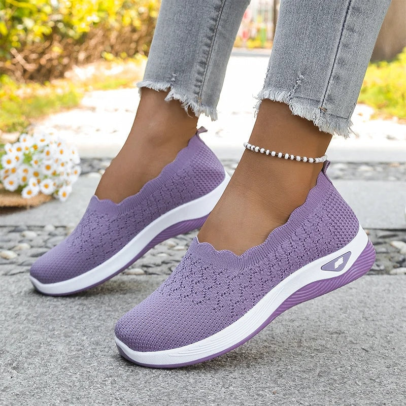 Zapatillas slip-on moradas con borde ondulado y suela acolchada, llevadas con vaqueros.
