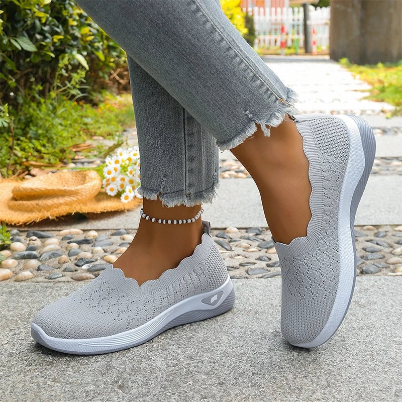 Zapatillas grises vistas desde un ángulo lateral, con un pie apoyado y el otro elevado.