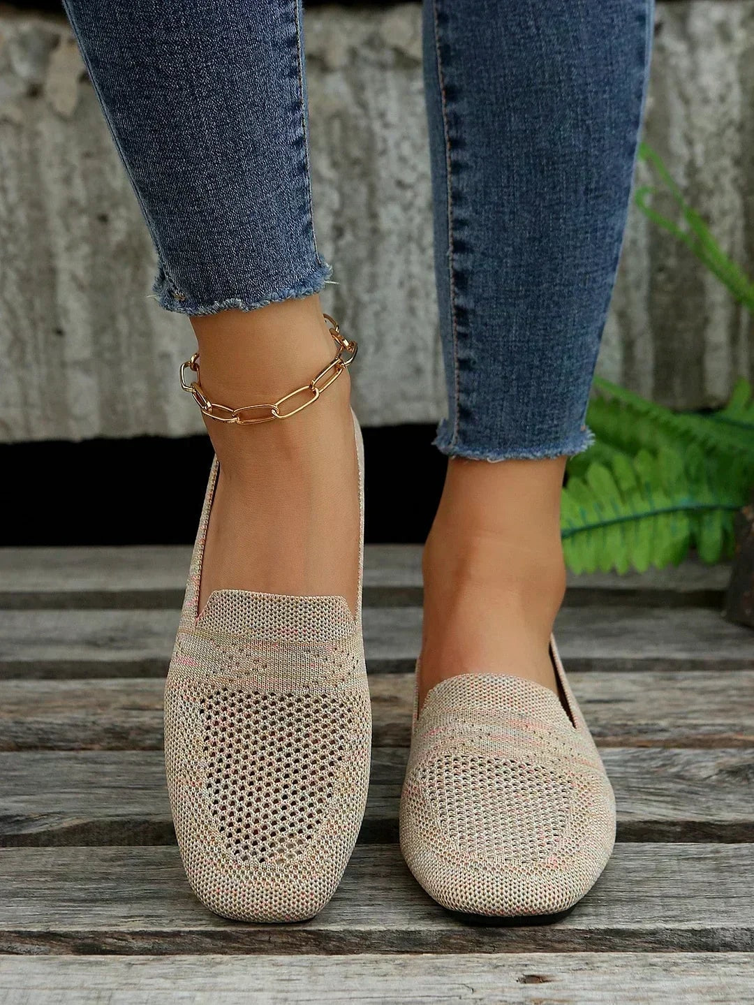 Par de zapatos planos beige de diseño calado vistos de frente, combinados con pantalones vaqueros.