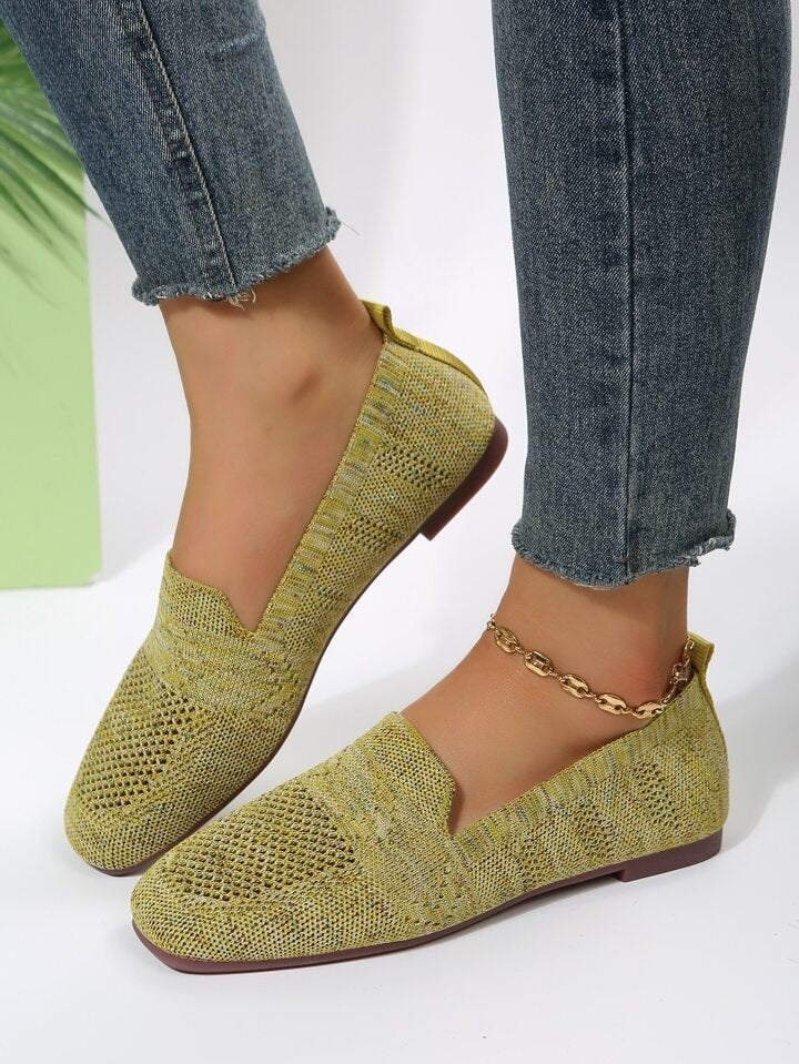Zapatos planos amarillos de puntera redondeada y suela marrón, llevados con pantalones vaqueros.