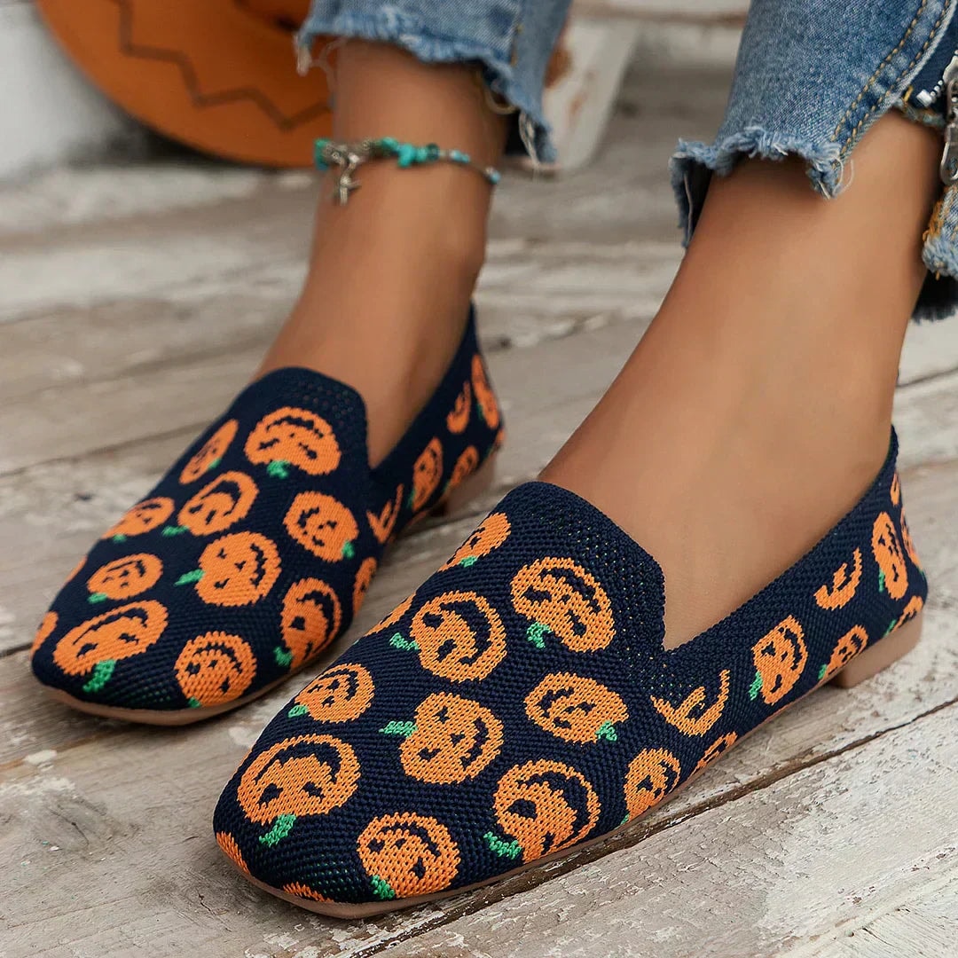Zapatos planos azul marino con estampado repetido de calabazas naranjas y pequeños detalles verdes.